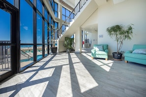 A spacious balcony with a pool view, modern architecture, and comfortable seating areas. - Phoenix I 1114 1 Bedroom Condo (Orange Beach)