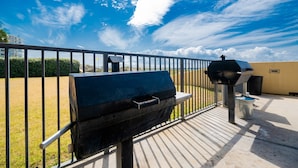 A barbecue grill and a water fountain on an outdoor deck with a metal railing. - Phoenix V 911 1 Bedroom Condo (Orange Beach)