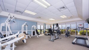 A gym with various exercise equipment, large windows, and a view of the outdoors. - Phoenix V 814 1 Bedroom Condo (Orange Beach)