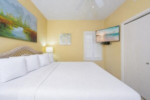 A bedroom with a bed, a painting, a television, and a window with blinds. - Phoenix V 1211 1 Bedroom Condo (Orange Beach)