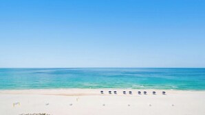 Ein Strand mit einer Reihe von Sonnenschirmen und Liegestühlen entlang der Küste.