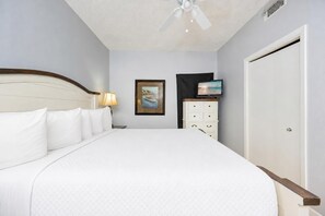 Une chambre d’hôtel avec un grand lit, une table de chevet, une lampe, un téléviseur, un tableau et une armoire.