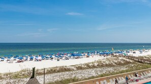 A beach with numerous umbrellas and sun loungers, a wooden boardwalk, and a clear view of the ocean. - Phoenix V 214 1 Bedroom Condo (Orange Beach)