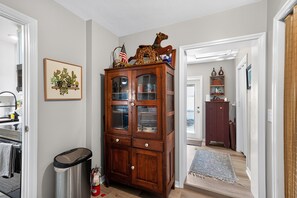A hallway with a wooden cabinet, a trash can, and a framed picture of cacti. - Chef's Kitchen Family Basecamp Vero Beach 2 Bedroom Home (Vero Beach)