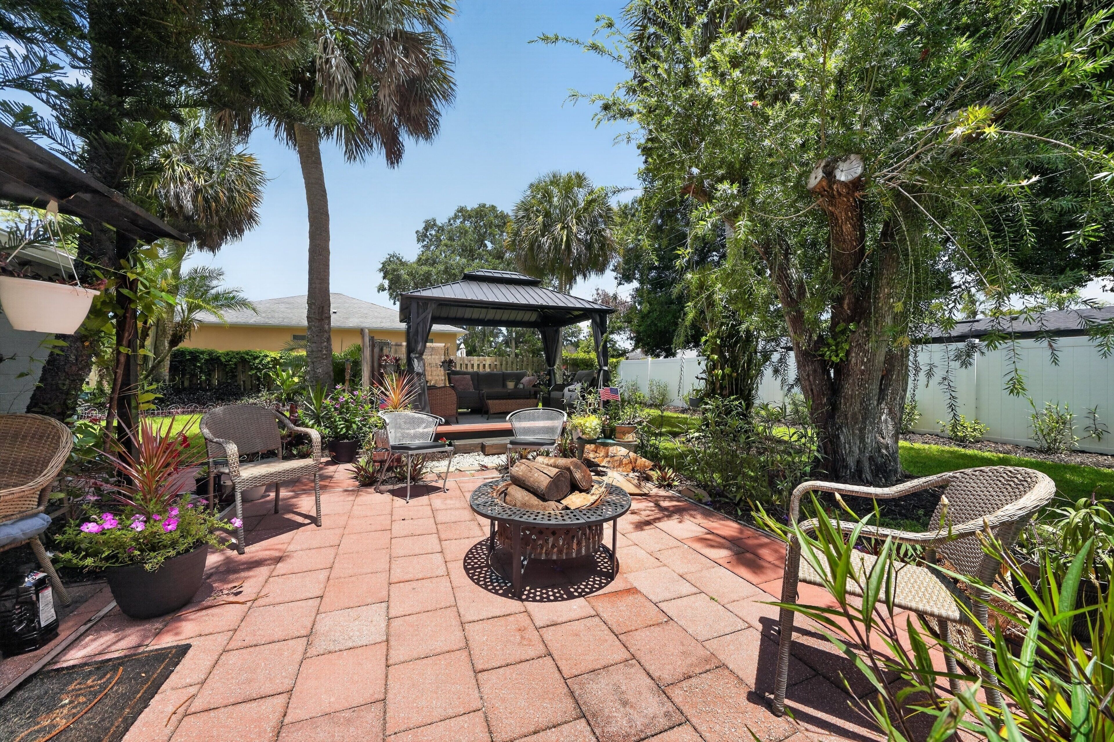 Un patio con pérgola, mobiliario exterior y un brasero.
