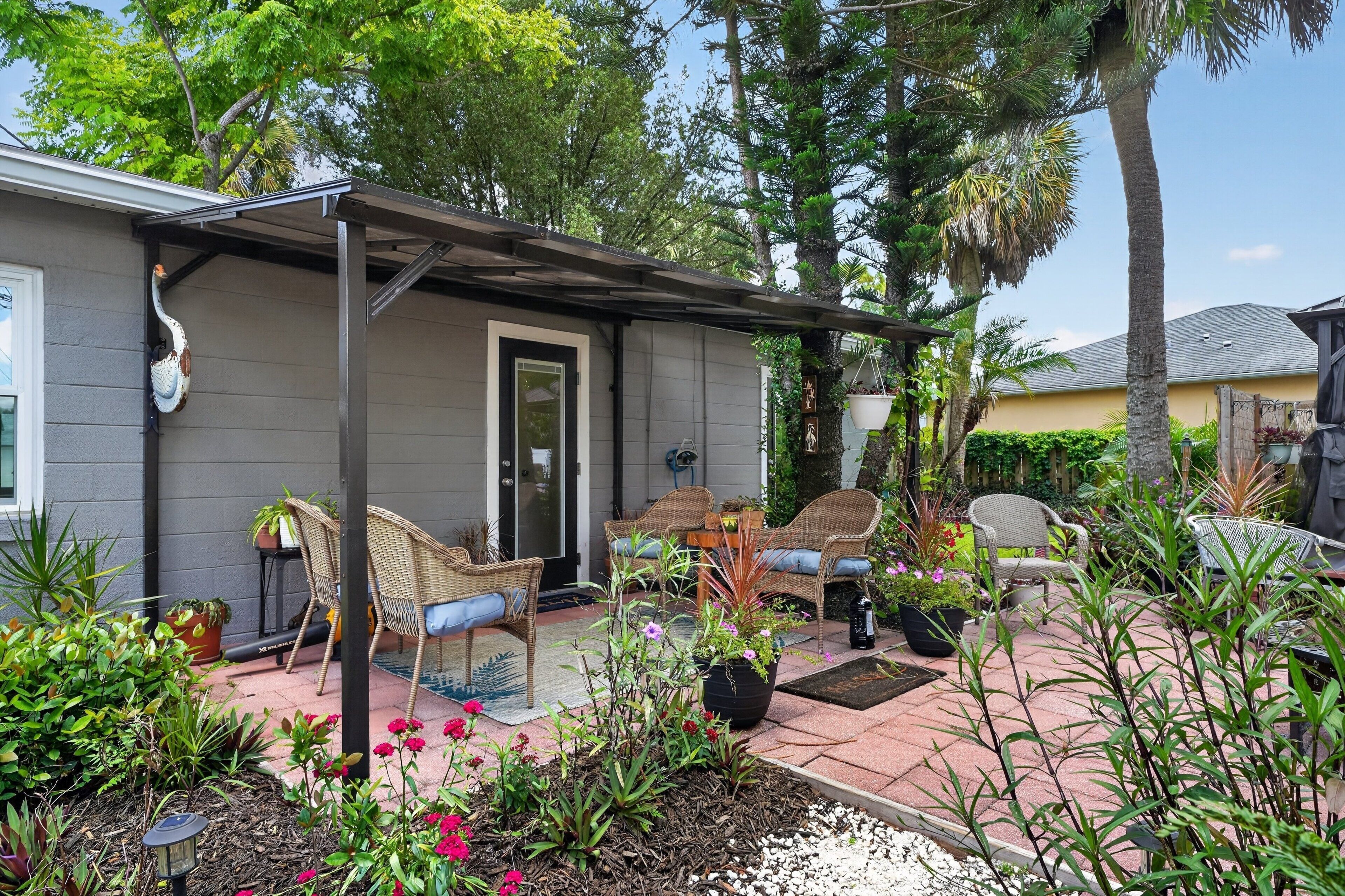 A covered patio area with wicker furniture, potted plants, and a bird sculpture.
