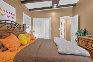 Un dormitorio con cama, almohadas, mesita de noche, lámpara, armario y puerta.