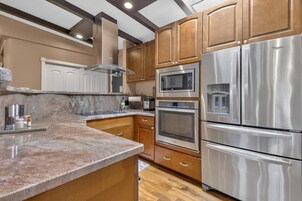 Una cocina moderna con electrodomésticos de acero inoxidable, armarios de madera y encimera de granito.