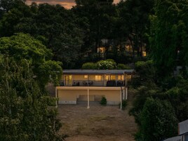 Una casa moderna con porche cubierto y jardín cercado.