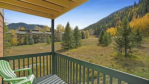 Eine überdachte Veranda mit Blick auf einen Berg und Wald.