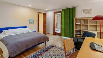 A bedroom with a bed, a desk with a chair, a bookshelf, and a door leading to another room.