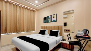 Una camera d'albergo con un letto, una sedia, un tavolo con un bollitore e uno specchio.