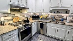 Een moderne keuken met witte kastjes, een gasfornuis, een oven, een magnetron en een spoelbak.