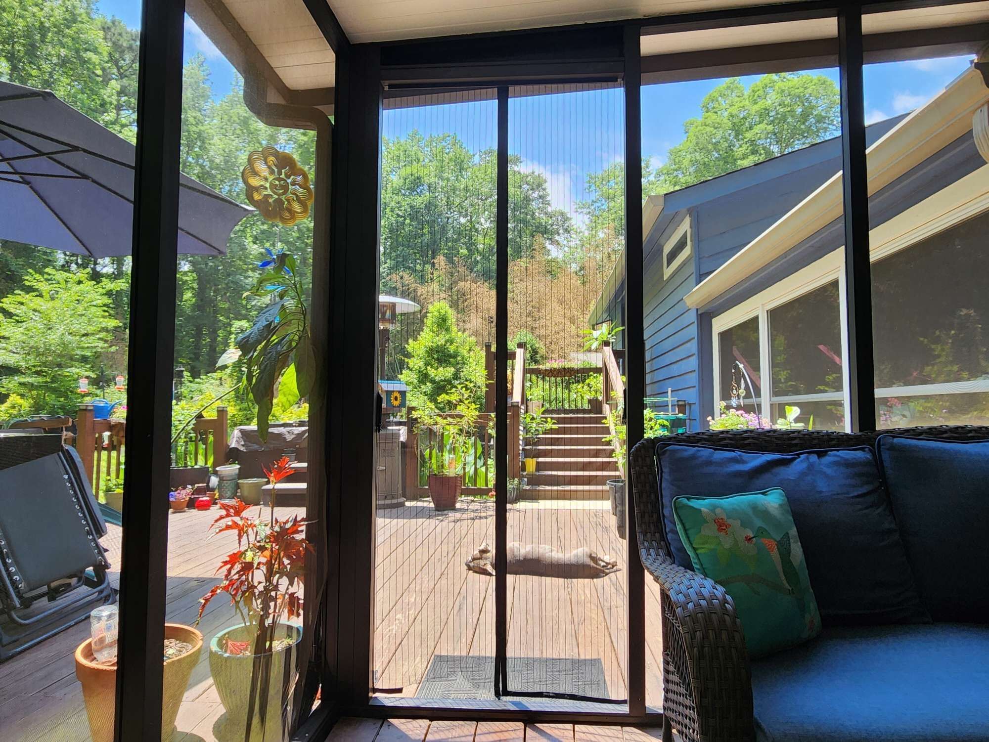 A covered patio with a sliding glass door leading to a backyard.