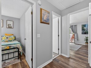Ein Zimmer mit einem Bett, einer Tür zu einem anderen Raum und einem Gemälde an der Wand.
