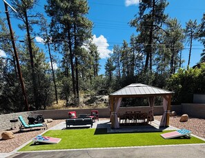 A gazebo with a roof, surrounded by outdoor furniture including chairs and a table, set on artificial grass with a view of tall trees and a clear sky. - Modern Prescott Hideaway-Within 1 Mile of Downtown - Fully Fenced / Private Yard (Prescott)