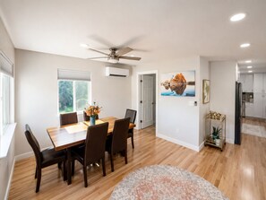 A modern dining area with a wooden table and chairs, a ceiling fan, and a view of the outdoors through a window. - Modern Prescott Hideaway-Within 1 Mile of Downtown - Fully Fenced / Private Yard (Prescott)