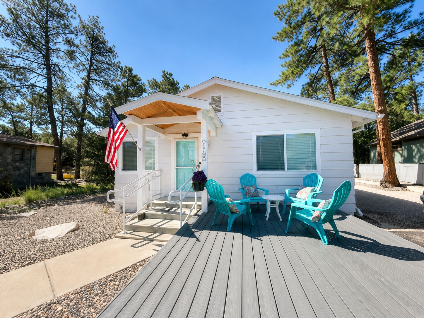 A small cabin with a porch, outdoor seating, and an American flag.