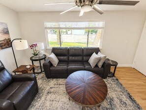 A living room with a leather sofa, a round coffee table, a floor lamp, and a window with blinds. - Modern Prescott Hideaway-Within 1 Mile of Downtown - Fully Fenced / Private Yard (Prescott)
