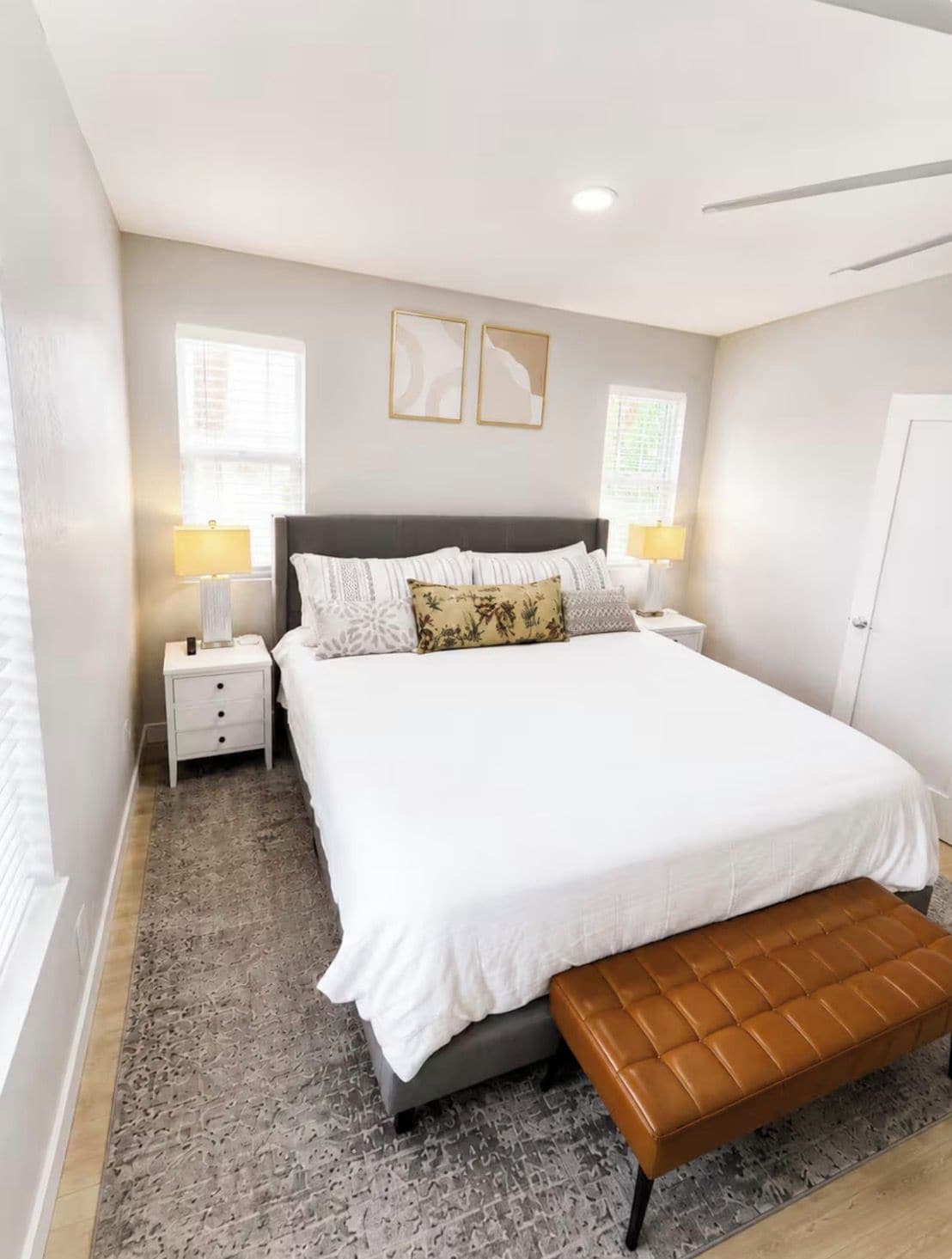 A bedroom with a large bed, two bedside tables, a bench, and two wall-mounted lamps.
