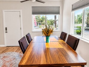 A dining area with a wooden table, four chairs, a vase with flowers, and a view of the outdoors through a window. - Modern Prescott Hideaway-Within 1 Mile of Downtown - Fully Fenced / Private Yard (Prescott)