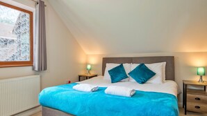 Ein Schlafzimmer mit einem Bett, zwei Nachttischen, einem Fenster mit Vorhängen und einer Heizung.