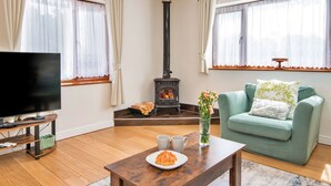 Ein Wohnzimmer mit Fernseher, einer Couch, einem Tisch mit Teller und Tassen sowie einem Kamin.