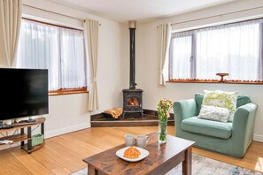 Una sala de estar con televisor, sofá, una mesa con plato y tazas, y chimenea.