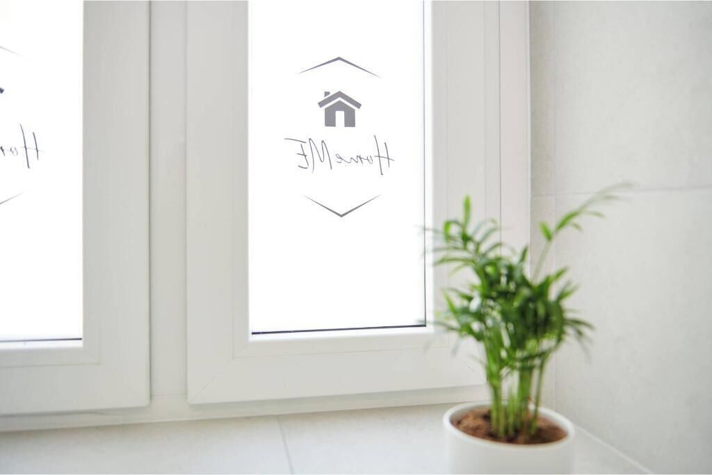 Une fenêtre avec une icône représentant une maison et du texte, une plante en pot et un mur blanc.