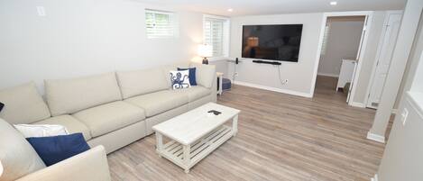 Un salon comprenant un canapé, une table basse et un téléviseur à écran plat fixé au mur.