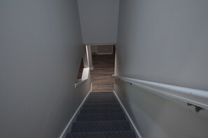 A narrow stairway with a handrail on one side and a wooden floor on the other, leading to a landing. - Downtown Rehoboth Beach Cozy Beach Getaway! (Rehoboth Beach)