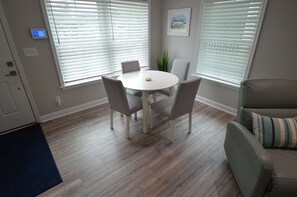 A dining area with a round table and four chairs, a potted plant, and a painting on the wall. - Downtown Rehoboth Beach Cozy Beach Getaway! (Rehoboth Beach)