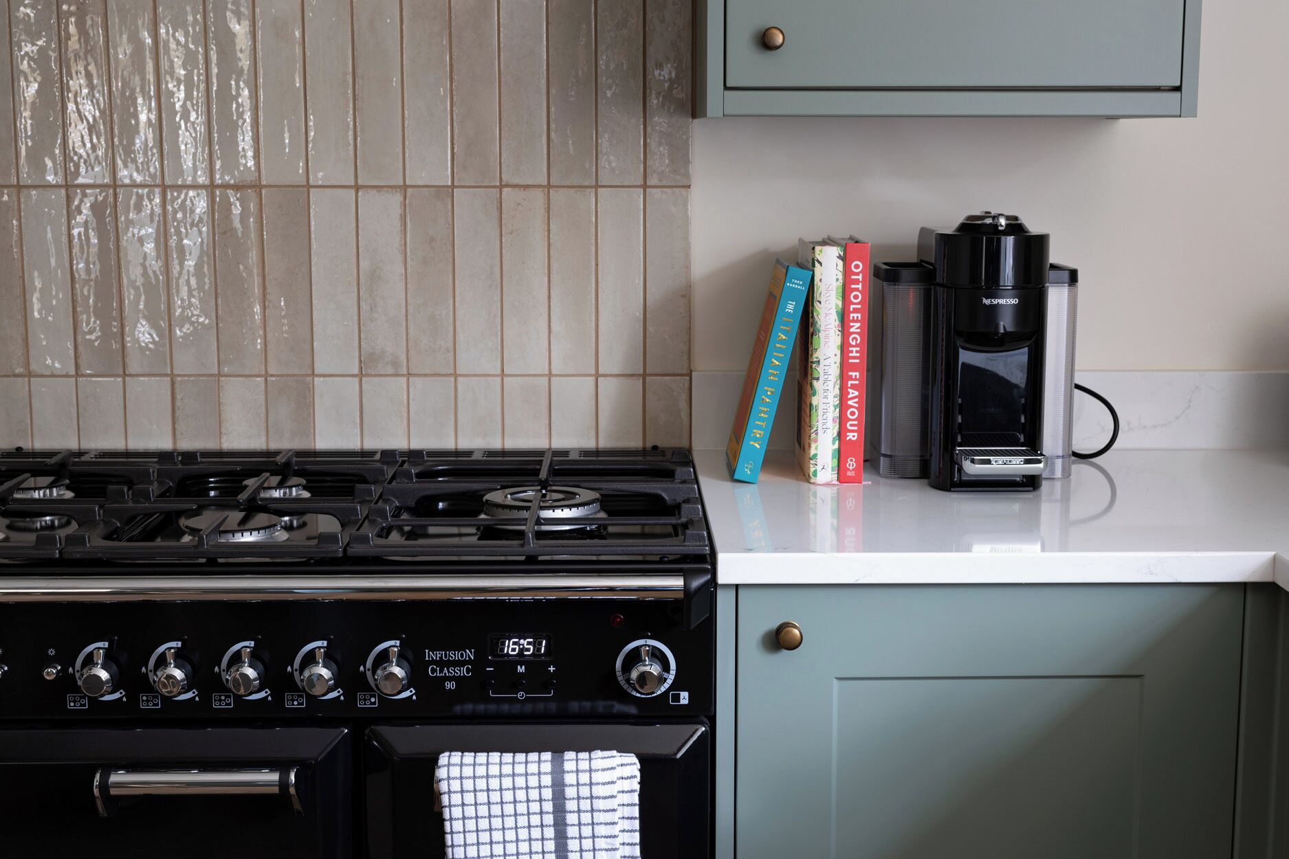 A kitchen with a gas stove, a coffee maker, and cookbooks on the counter.