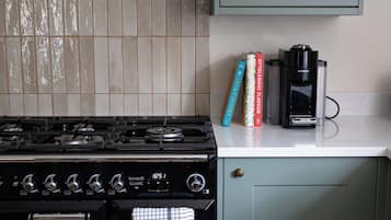A kitchen with a gas stove, a coffee maker, and cookbooks on the counter.
