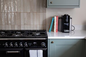 Una cocina con estufa a gas, cafetera y libros de cocina sobre la encimera.