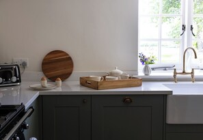 A kitchen with a wooden cutting board, a toaster, and a tray of cups on the counter.