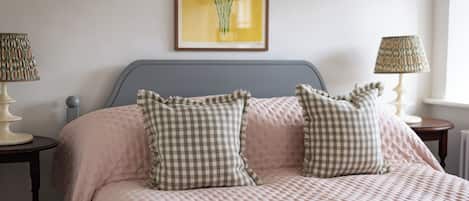 A bedroom with a bed, two bedside lamps, a wall-mounted picture, and a window.