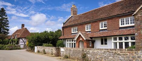 A traditional two-story house with a stone wall and a tiled roof.
