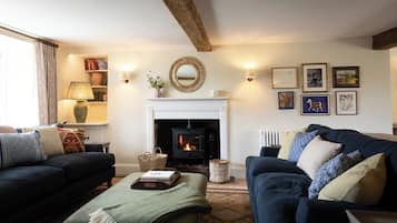 A cozy living room with a fireplace, two sofas, a coffee table, and a bookshelf.