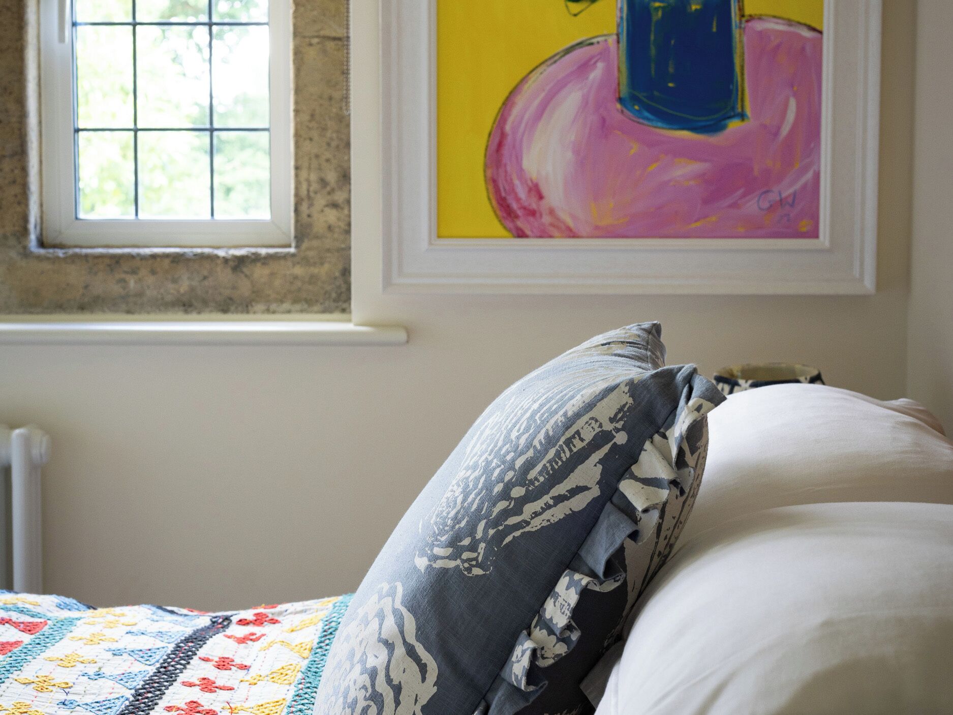 A bedroom with a bed, a window, and a painting on the wall.
