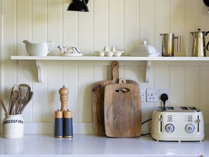 A kitchen with white cabinetry, a wooden cutting board, a vintage toaster, and various kitchen utensils. - Costers Lodge (Midhurst)