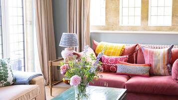 Una sala acogedora con un sofá, una mesa de centro con un florero y una lámpara.
