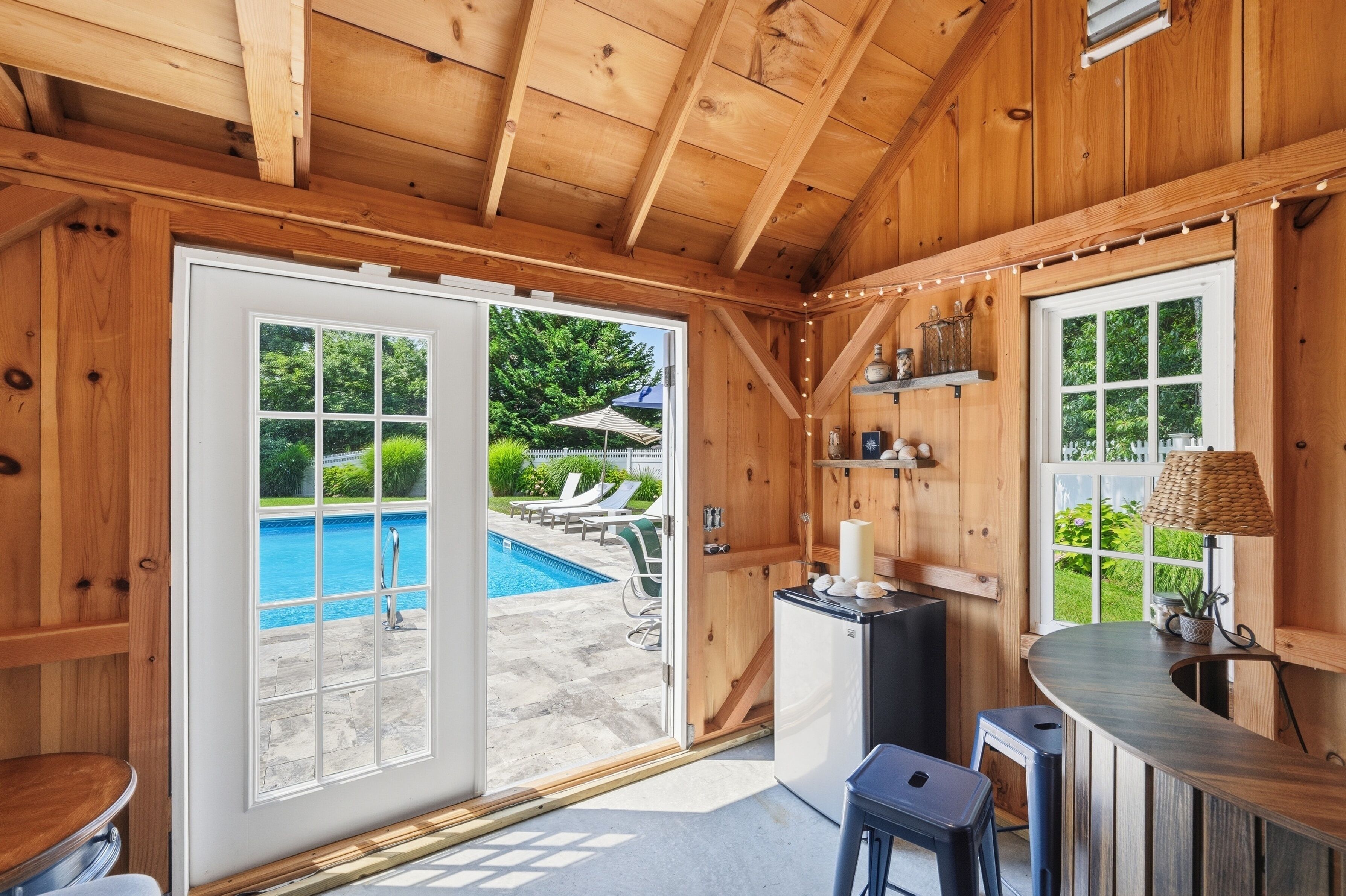 A wooden cabin interior with a pool, outdoor seating, and a bar area.