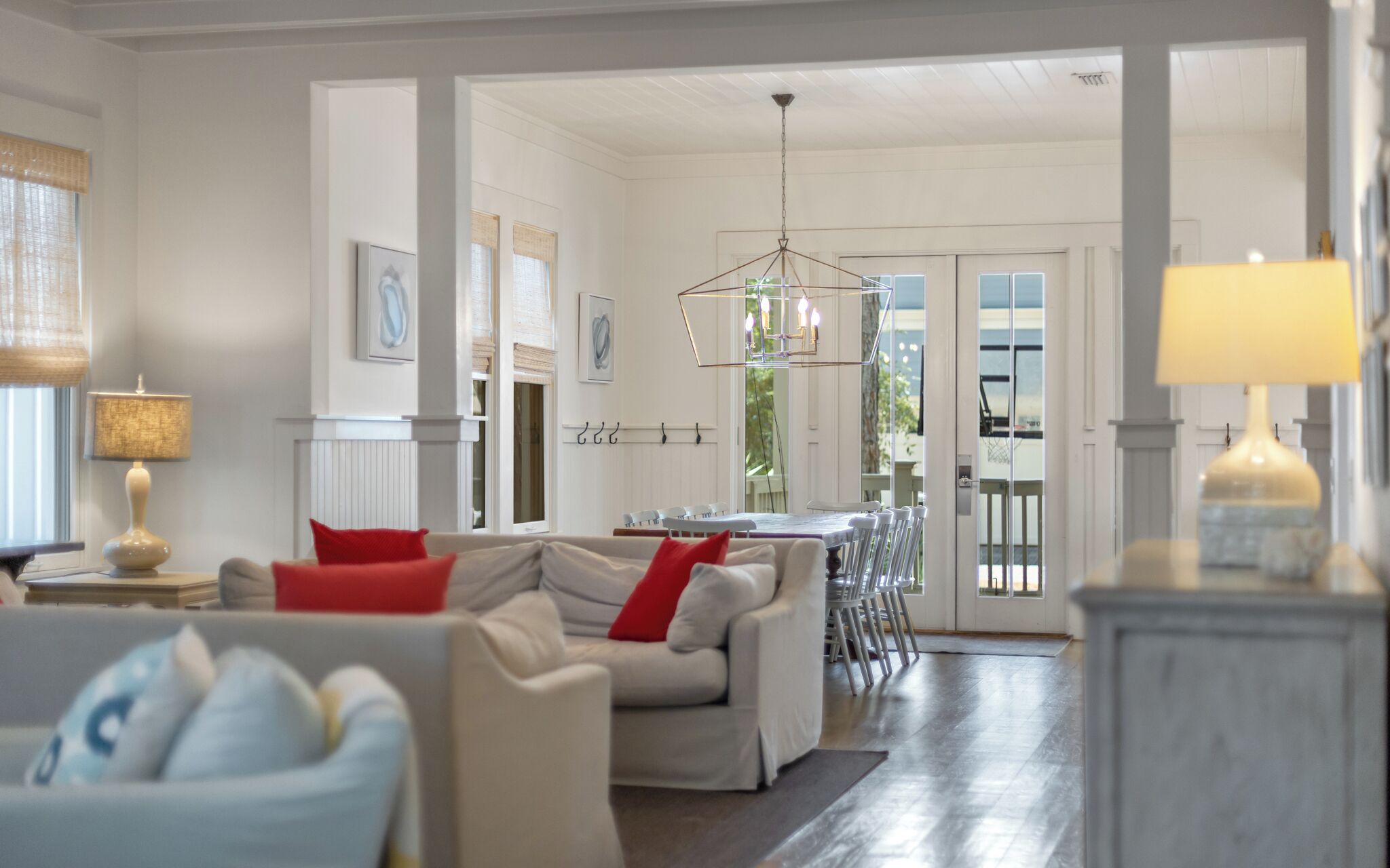A spacious living room with a dining area, featuring a chandelier, a fireplace, and a view through a glass door.