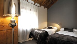 A bedroom with two beds, a lamp, and a window with curtains. - The Queixans Cabin with a Fireplace (Queixans)