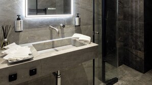 Een moderne badkamer met een grote spiegel, twee wasbakken en een douche met glazen wanden.