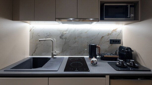 Een moderne keuken met een ingebouwde magnetron, een gootsteen met kraan en een kookplaat.
