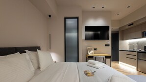 Een moderne hotelkamer met een groot bed, een bureau, een flatscreen televisie en een kitchenette.