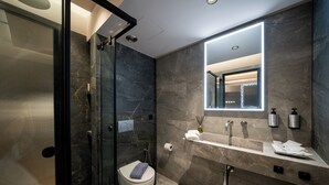 A modern bathroom with a glass shower enclosure, a toilet, a vanity with a mirror, and a sink.