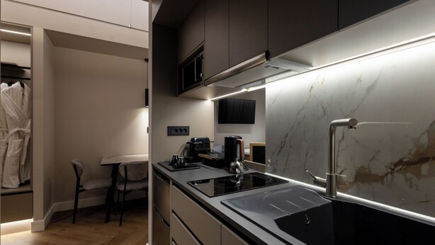 A modern kitchen with a marble backsplash, stainless steel appliances, and a dining area with a table and chairs.